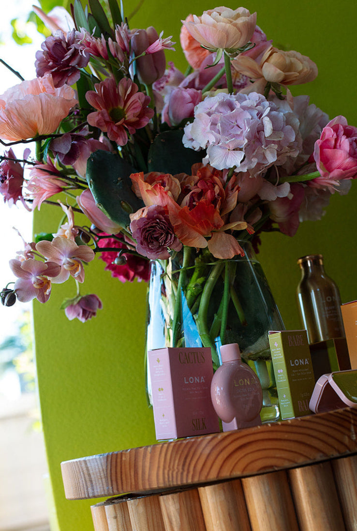 Bouquet of flowers on a wooden stand with perfume bottles against a green wall in Austin Texas.