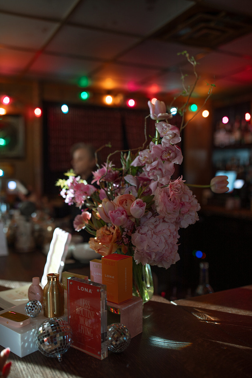 Decorative setup with flowers, bottles, and boxes on a table with a blurred indoor background in Austin Texas.