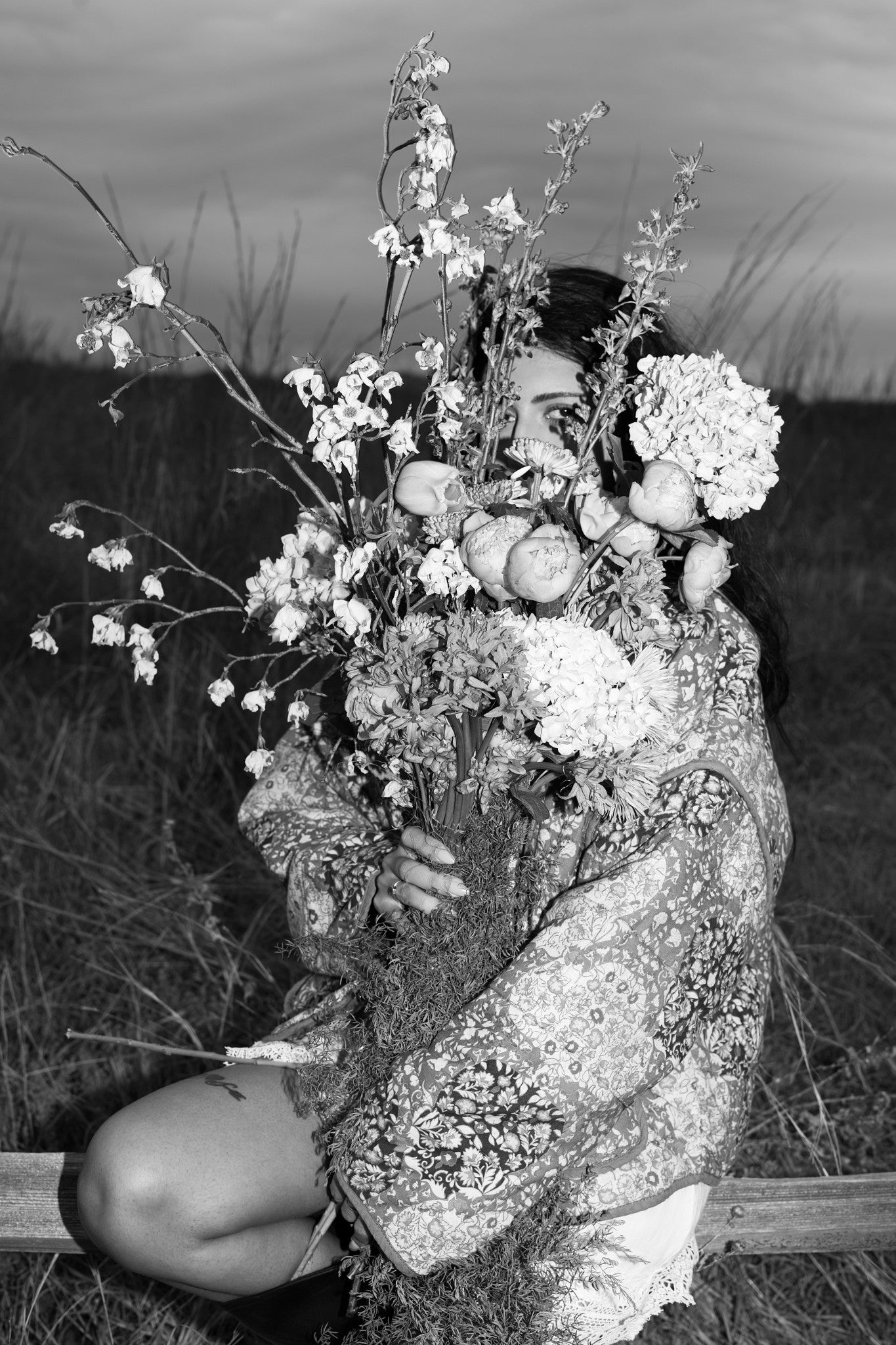Person holding a bouquet of flowers in a black and white photograph