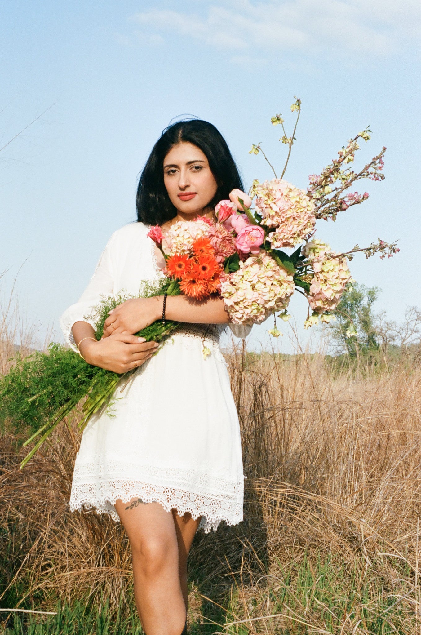 Woman in a white dress holding a bouquet of flowers in a field in Austin Texas