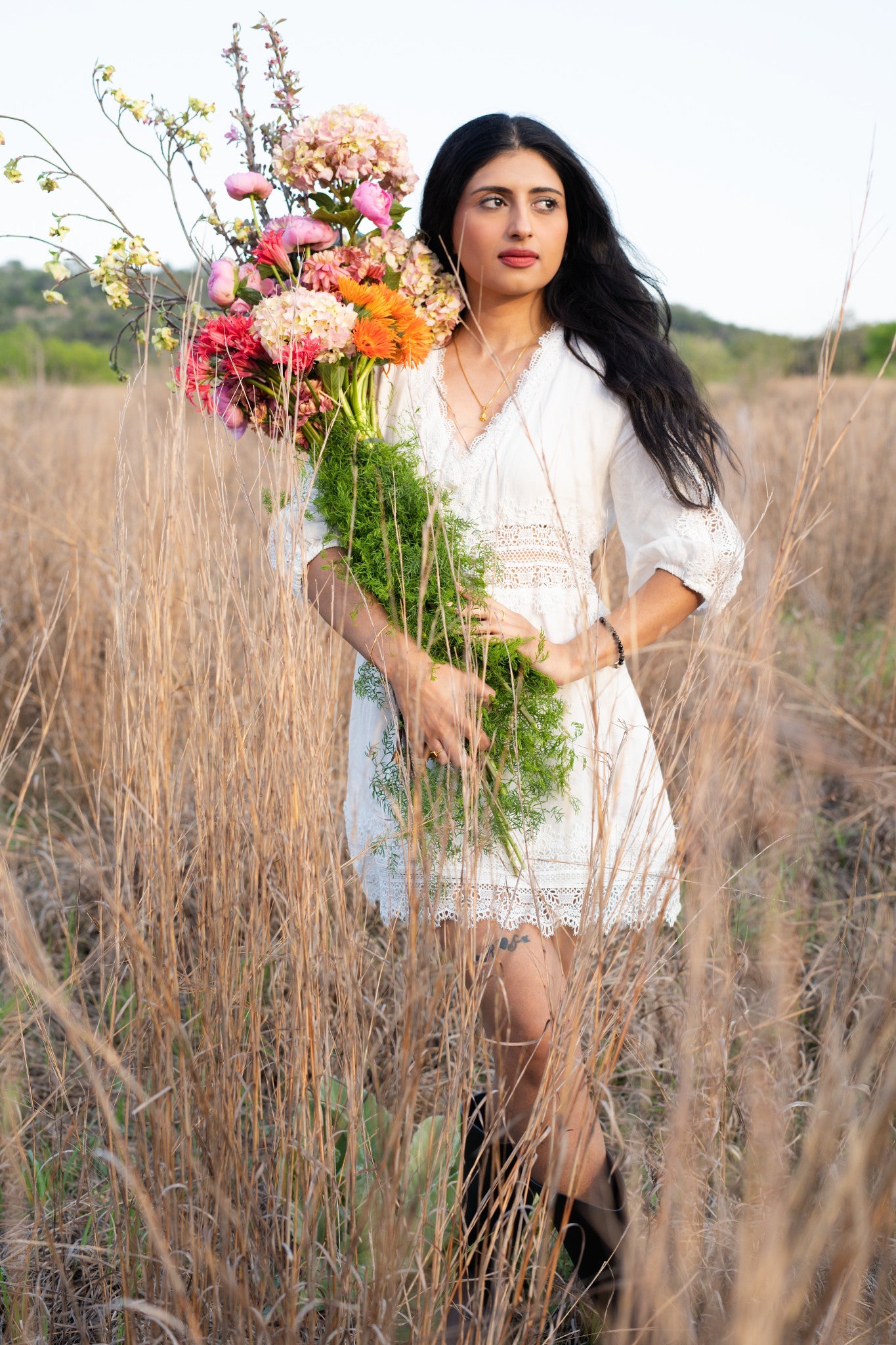 Woman holding flowers in a field with a scenic background in Austin Texas